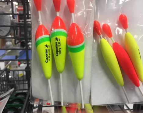 Drei bunte Angelposen aus Schaumstoff in einem Verkaufsregal mit auffälligen, leuchtenden Farben.