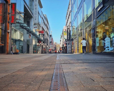 Hohe Straße Die Hohe Straße in Köln zeigt eine belebte Einkaufsstraße mit modernen Glasfassaden und Menschen.Hohe Strasse in Cologne is a busy shopping street with modern glass facades and people.