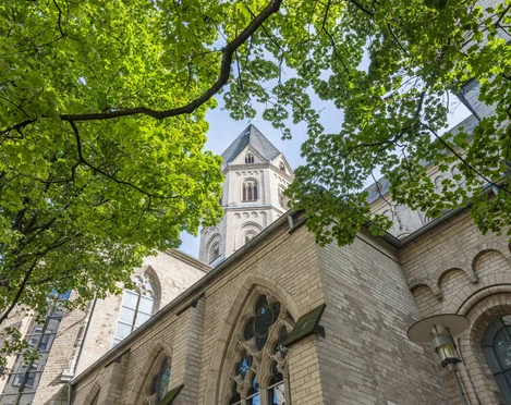 St. Andrew Romanische Kirche St. Andreas, harmonische Mischung aus Backsteinarchitektur und grünem Laub.Romanesque church of St. Andrew, harmonious blend of brick architecture and green foliage.