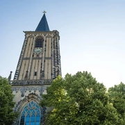 Saint Severin Historische Kirche Sankt Severin mit prächtigem Uhrturm, umgeben von grünen Baumkronen.Historic church of St. Severin with a magnificent clock tower, surrounded by green treetops.