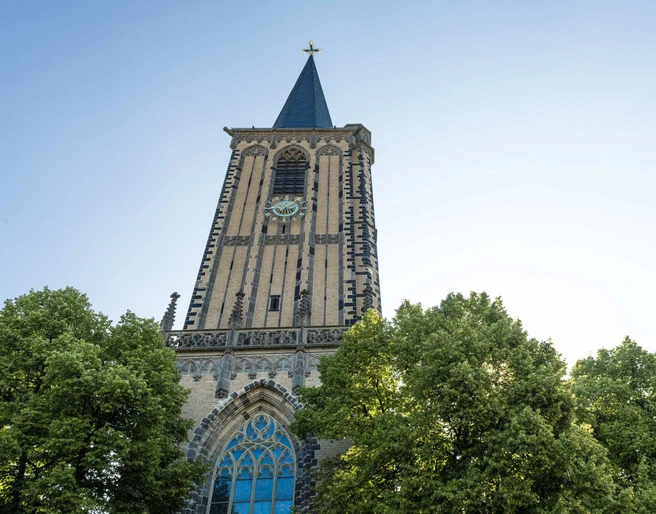 Saint Severin Historische Kirche Sankt Severin mit prächtigem Uhrturm, umgeben von grünen Baumkronen.Historic church of St. Severin with a magnificent clock tower, surrounded by green treetops.