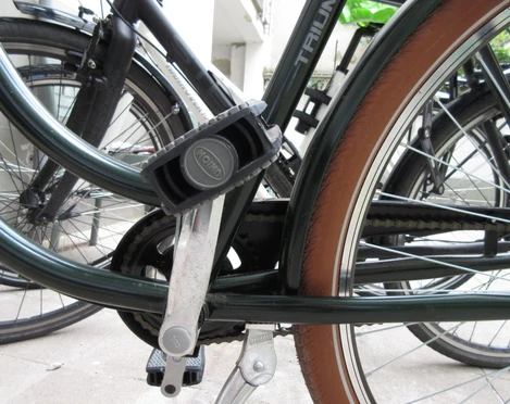 Rad Ein schwarzes Fahrrad steht auf einem Betonboden; ein Pedal und die Kettenlöcher sind im Fokus.