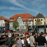Neustadtmarktplatz Menschen versammeln sich auf einem belebten Marktplatz mit Fachwerkhäusern und Tischen unter freiem Himmel.