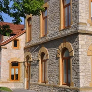 Rathaus Oerlinghausen Steinernes Rathausgebäude mit großen Fenstern und rötlichem Rahmen, umgeben von Bäumen im Sonnenschein.