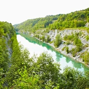 Lengericher Canyon Smaragdgrüner See eingerahmt von bewaldeten Klippen, umgeben von üppiger Vegetation.