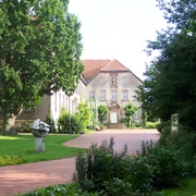 Kloster Willebadessen Historisches Kloster Willebadessen mit Ziegelsteingebäude, umgeben von grünen Bäumen und gepflegten Gärten.