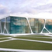 Modernes Gebäude mit großen Glasflächen und geschwungener Architektur in einer grünen Landschaft.