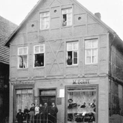 Haus Schiff Historisches Fachwerkhaus mit Menschen an Fenstern und Eingang, Schaufenster mit Hüten und Waren.