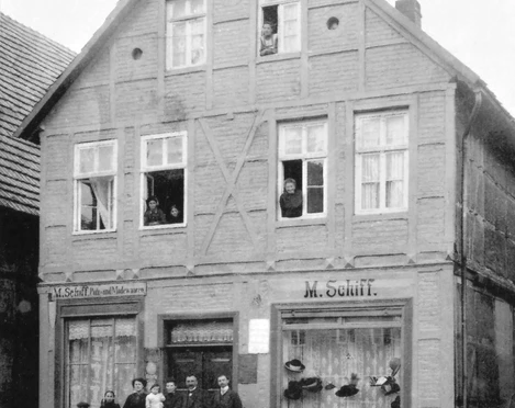 Haus Schiff Historisches Fachwerkhaus mit Menschen an Fenstern und Eingang, Schaufenster mit Hüten und Waren.