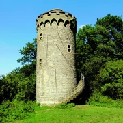 Auf unserer Wanderung kommen wir am Holsterturm vorbei. Ein historischer Steinturm mit Wendeltreppe steht von Bäumen umgeben im Grünen unter klarem Himmel.