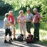 Wandergruppe Eine Gruppe von fünf Senioren plaudert auf einem Waldweg. Sie tragen lässige Wanderbekleidung.