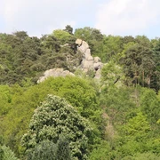 Felsformation Hockendes Weib Felsformation aus hellem Gestein ragt aus einem dichten, grünen Wald mit vielfältiger Vegetation.
