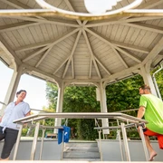 Kneipp-Vitalpark Eine Frau und ein Mann entspannen sich und unterhalten sich in einem hölzernen Pavillon im Freien.