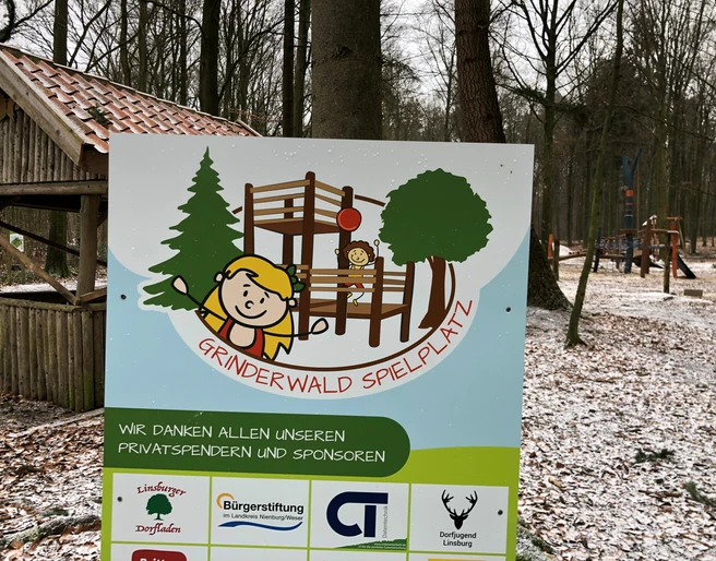 Grinderwald Spielplatz Ein verschneiter Spielplatz im Grinderwald, umgeben von Bäumen, mit Holzklettergerüst und Schaukeln.