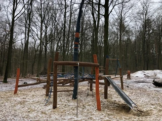 Grinderwald Spielplatz Moderner Waldspielplatz mit Klettergerüst, Rutsche und Seilstrukturen in winterlichem Waldambiente.