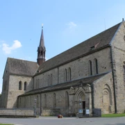 Kloster Loccum Mittelalterliche Klosterkirche aus Stein mit rotem Turm vor blauem Himmel, umgeben von Gärten.