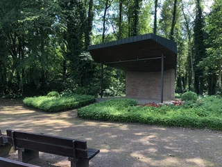 Bühne Kurpark Bruchhausen-Vilsen Eine überdachte Bühne im Kurpark Bruchhausen-Vilsen, umgeben von grüner Vegetation und Parkbänken.