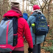 Wandern Mehrere Wanderer in bunter Outdoorkleidung auf einem Pfad im herbstlichen, bewaldeten Gelände.