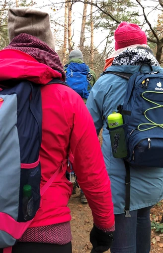 Wandern Mehrere Wanderer in bunter Outdoorkleidung auf einem Pfad im herbstlichen, bewaldeten Gelände.