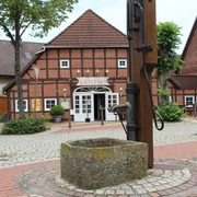 Ortsmitte Bruchhausen-Vilsen Historisches Fachwerkhaus mit Schriftzug "KAFFEEHAUS", umgeben von Pflastersteinen und Bäumen.