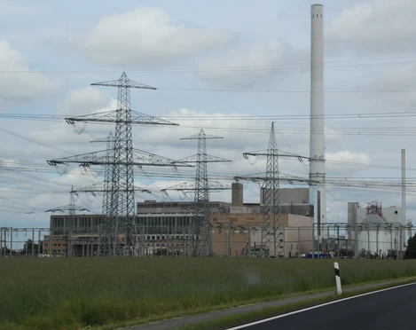 Landesbergen Kraftwerk Ein großes Kraftwerk mit hohen Schornsteinen und Strommasten vor bewölktem Himmel und Wiesen.