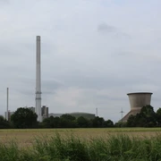 Landesbergen Kraftwerk Kraftwerk mit hohem Schornstein und Kühlturm umgeben von grünen Feldern und Bäumen an bewölktem Himmel.