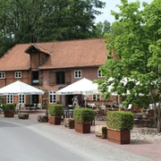 Klostermühle Heiligenberg Historische Backsteinmühle mit Biergarten, Holztischen und weißen Sonnenschirmen unter blühendem Baum.