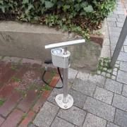 Lufttankstelle Luftstation mit Handpumpe für Fahrräder auf einem gepflasterten Bürgersteig, von Pflanzen umgeben.