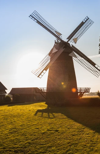 Lübbecke Windmühle Eilhausen Lübbecke Windmühle Eilhausen bei Sonnenuntergang, umgeben von grüner Wiese und Bäumen.