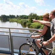 Weserbrücke Nienburg Zwei Radfahrer blicken von einer Brücke aus auf die beruhigende Weserlandschaft bei Nienburg.