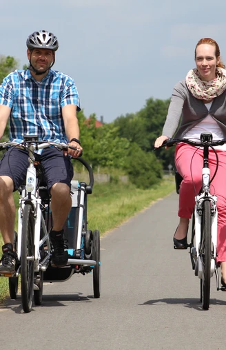 Radler Mittelweser Zwei Radfahrer fahren auf einem asphaltierten ländlichen Weg in einer grünen, bewaldeten Landschaft.