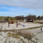 Trockenstrand Upleward Spielplatz Zu sehen sind mehrere Spielgeräte auf dem Trockenstrand in Upleward. Im Hintergrund der Deich,