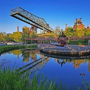 <p>Industrieanlage im Landschaftspark Duisburg-Nord mit Wasserbecken, blauer Himmel und grüner Natur.</p>