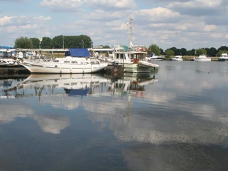 Marina Mehlbergen Boote liegen malerisch im ruhigen Wasser der Marina Mehlbergen, umgeben von bewölktem Himmel.