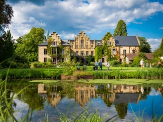 Schloss Ippenburg im Osnabrücker Land Historisches Gebäude mit Spitzgiebeln und bewachsenem Mauerwerk, Park und Teich im Vordergrund.