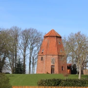 Windmühle Ruine Haßbergen Backsteinruine einer historischen Windmühle umgeben von Bäumen und Wiese unter blauem Himmel.