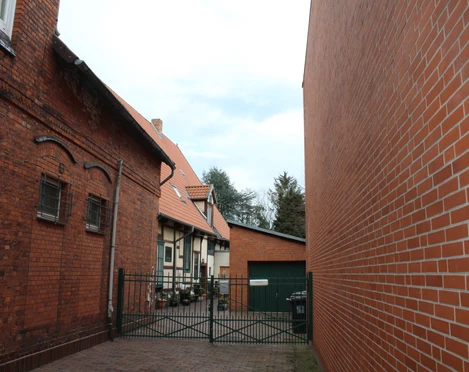 Beckmann Haus Backsteingebäude mit rotem Dach und Tor zu Hof, links ein Baum, rechts ein moderner Anbau.