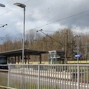 Bahnhof Langwedel Bahnhof mit blau-gelbem Zug, überdachter Wartebereich, umgeben von Bäumen unter bewölktem Himmel.