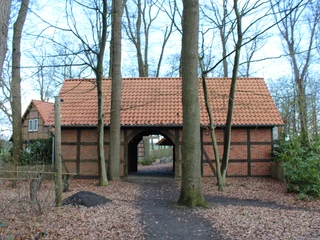 Freilichtbühne Holtebüttel Fachwerkgebäude mit rotem Ziegeldach, umgeben von kahlen Bäumen und einem mit Herbstlaub bedeckten Pfad.