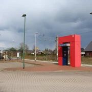 Bahnhof Lahde Bahnhof Lahde mit rotem Infoschalter und teils bewölktem Himmel, umgeben von typischen Gebäuden.