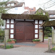 Bad Hopfenberg Historisches Fachwerkhaus mit großen Holztoren, umgeben von Pflanzen und daffodils im Vordergrund.
