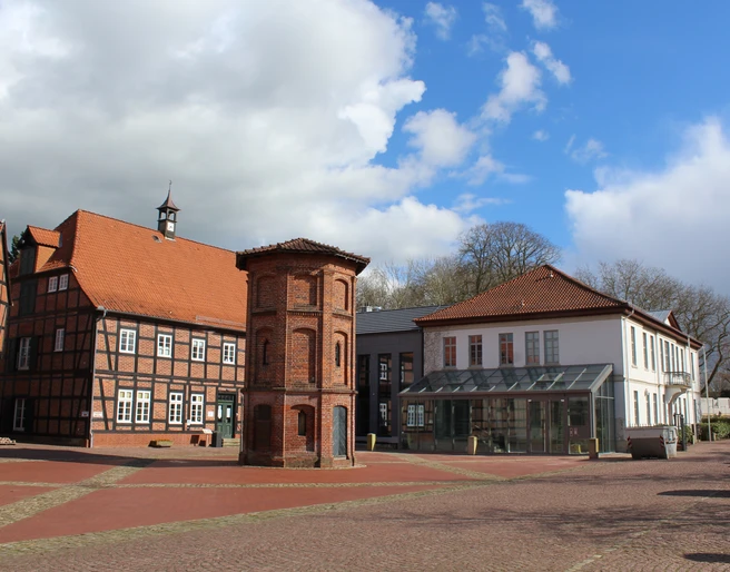 Rathaus Thedinghausen mit Fachwerkbauelementen und prägnantem quadratischem Eckturm bei blauem Himmel.