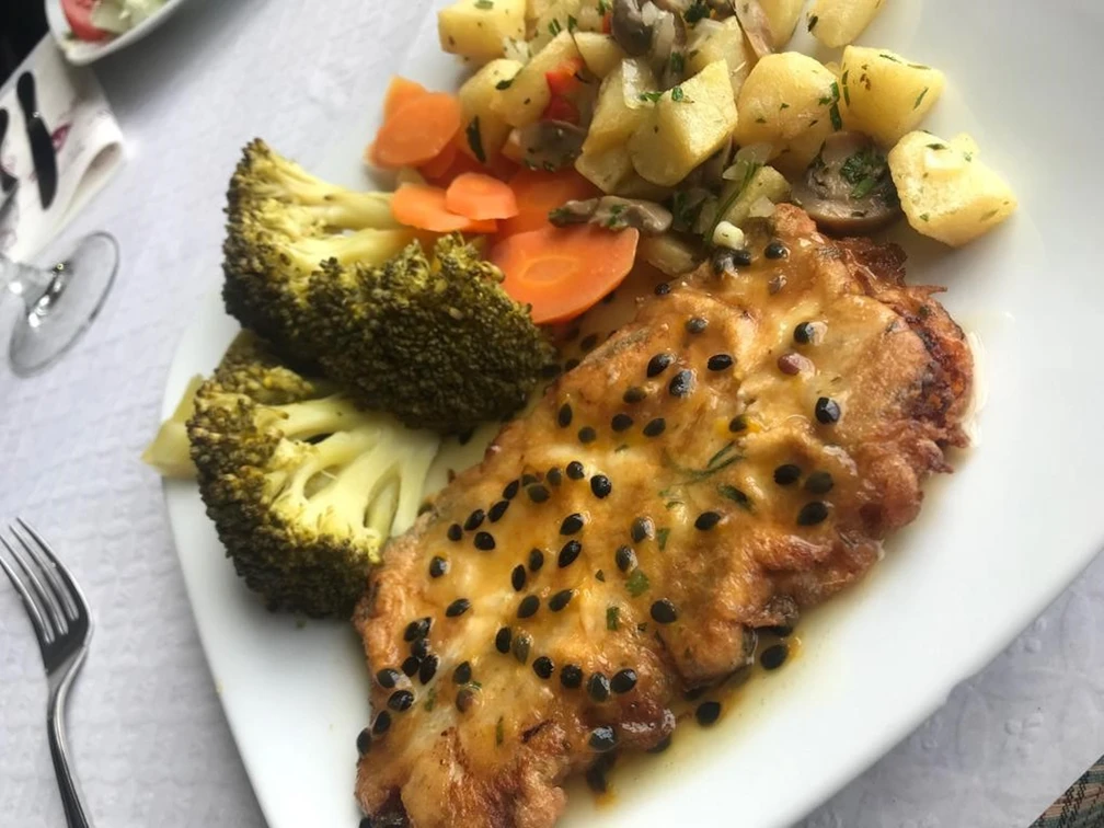 Fischgericht Ein köstlich angerichtetes Fischfilet mit Pfeffersoße, serviert mit Gemüse und Kartoffelwürfeln.