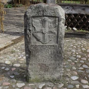 Steinmonument mit Wappen und Inschrift, umgeben von Pflastersteinen, im Außenbereich aufgenommen.