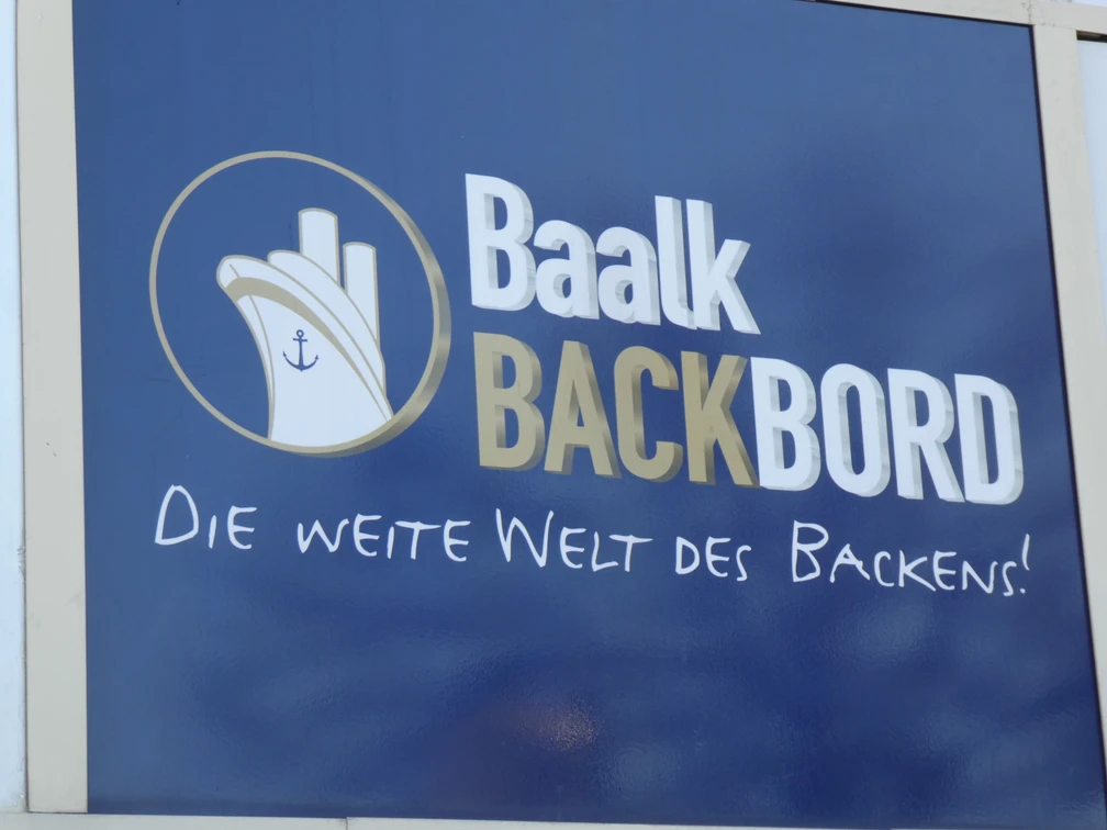 Baalk Backbord Logo auf blauem Hintergrund mit dem Slogan "Die weite Welt des Backens!".