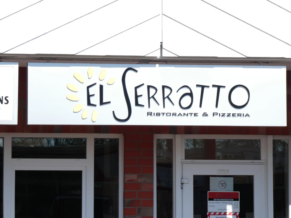 Eingang eines Restaurants mit dem Namen "El Serratto", Holzbalken und rotem Backstein in der Fassade.