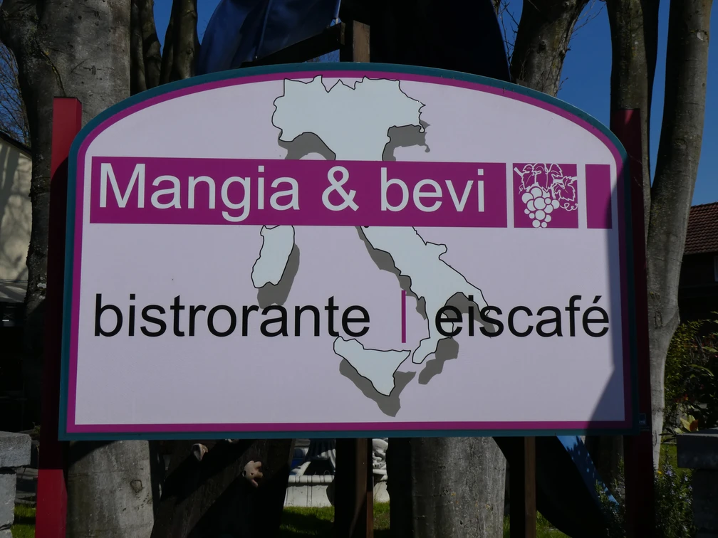 Mangia & Bevi Bistroschild mit Karte Italiens, Holzrahmen und laubumrahmtem Hintergrund.