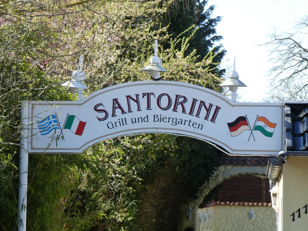 Restaurant Santorini Das Eingangsschild des Restaurants Santorini zeigt eine griechische und deutsche Flagge mit grüner Umgebung.