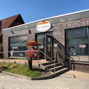 Der Leeser Dorfladen mit roter Ziegelverkleidung und ebenerdigem Zugang an einem sonnigen Tag.