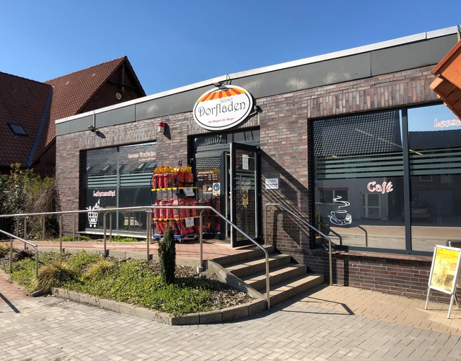 Leeser Dorfladen Der Leeser Dorfladen mit roter Ziegelverkleidung und ebenerdigem Zugang an einem sonnigen Tag.